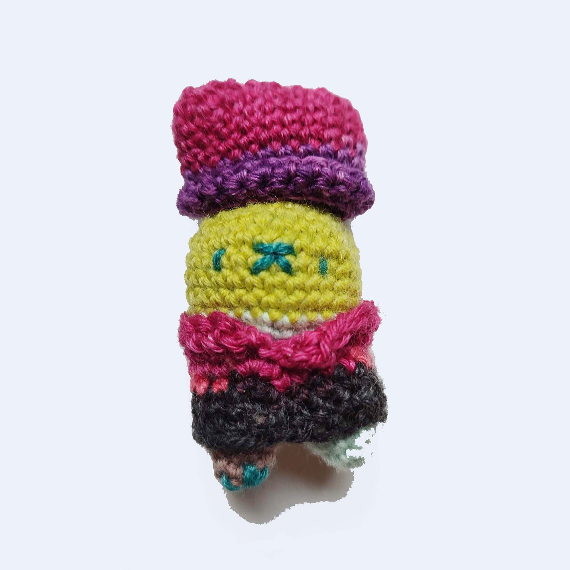 light green colored crocheted toy bun alien wearing a red hat and shirt