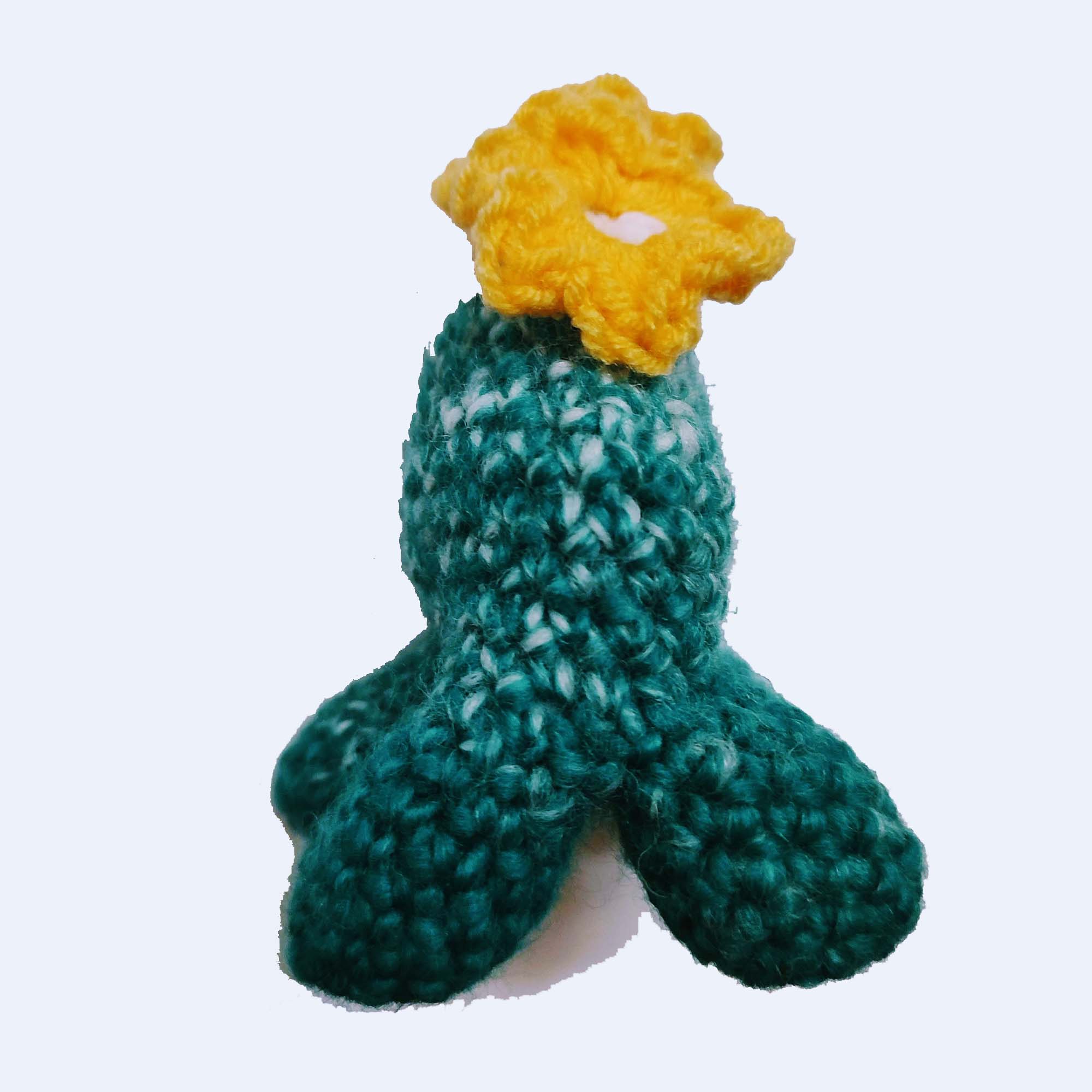green crocheted nunion toy with four legs, a faceless head with yellow flowers sprouting from it