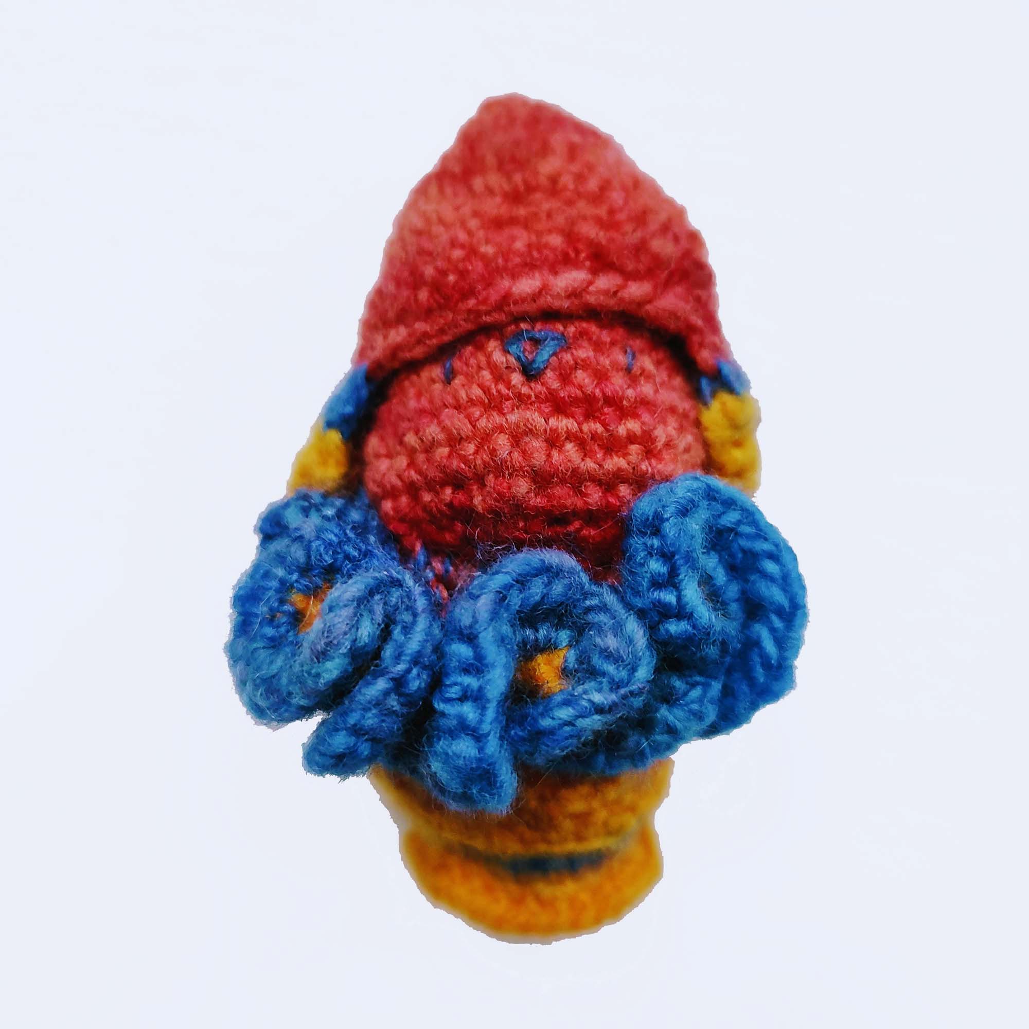 red, blue and yellow crocheted toy bun alien in a rocket pod