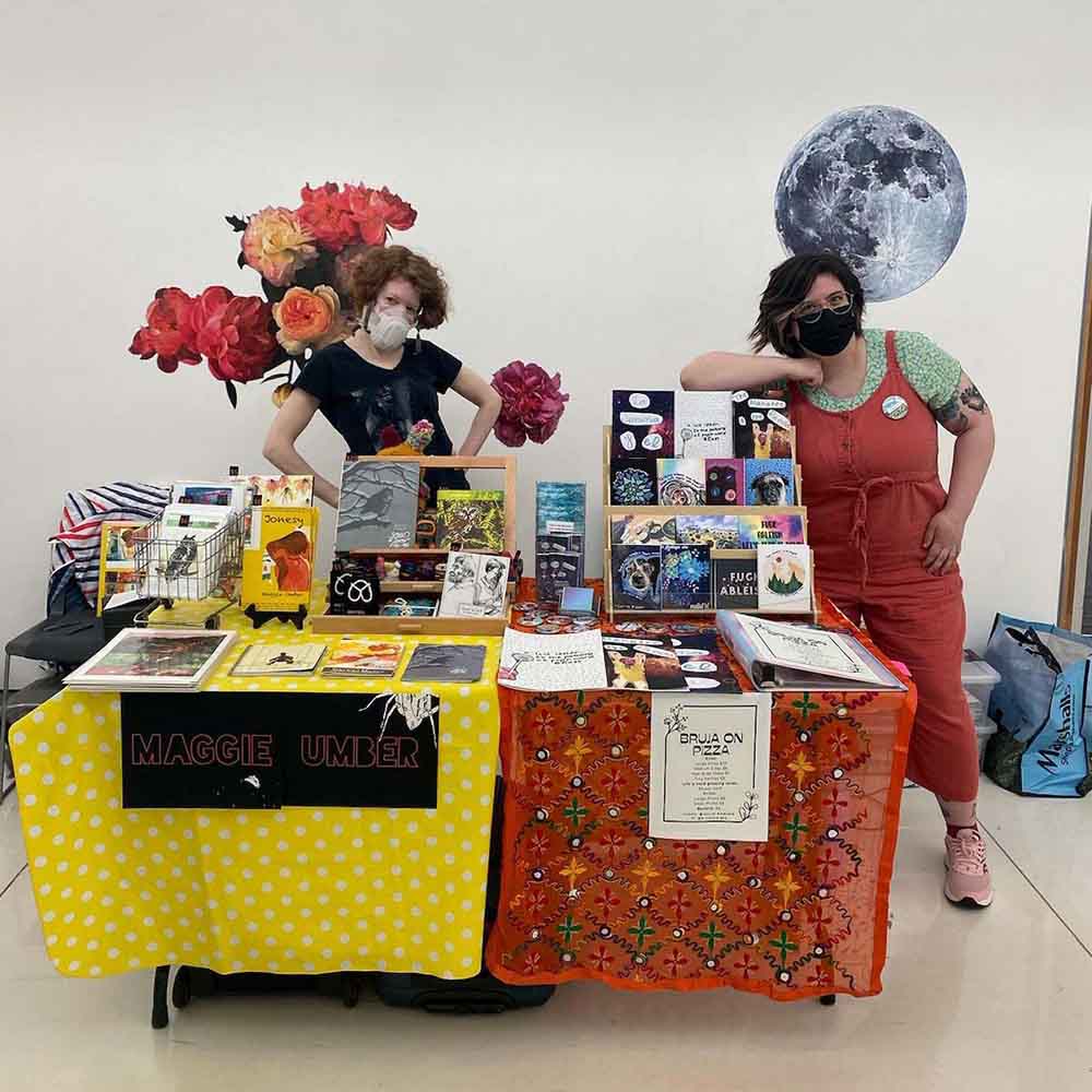 Maggie Umber and @brujaonpizza (Jenine) sharing a table at Madison Print and Resist Zine Fest
