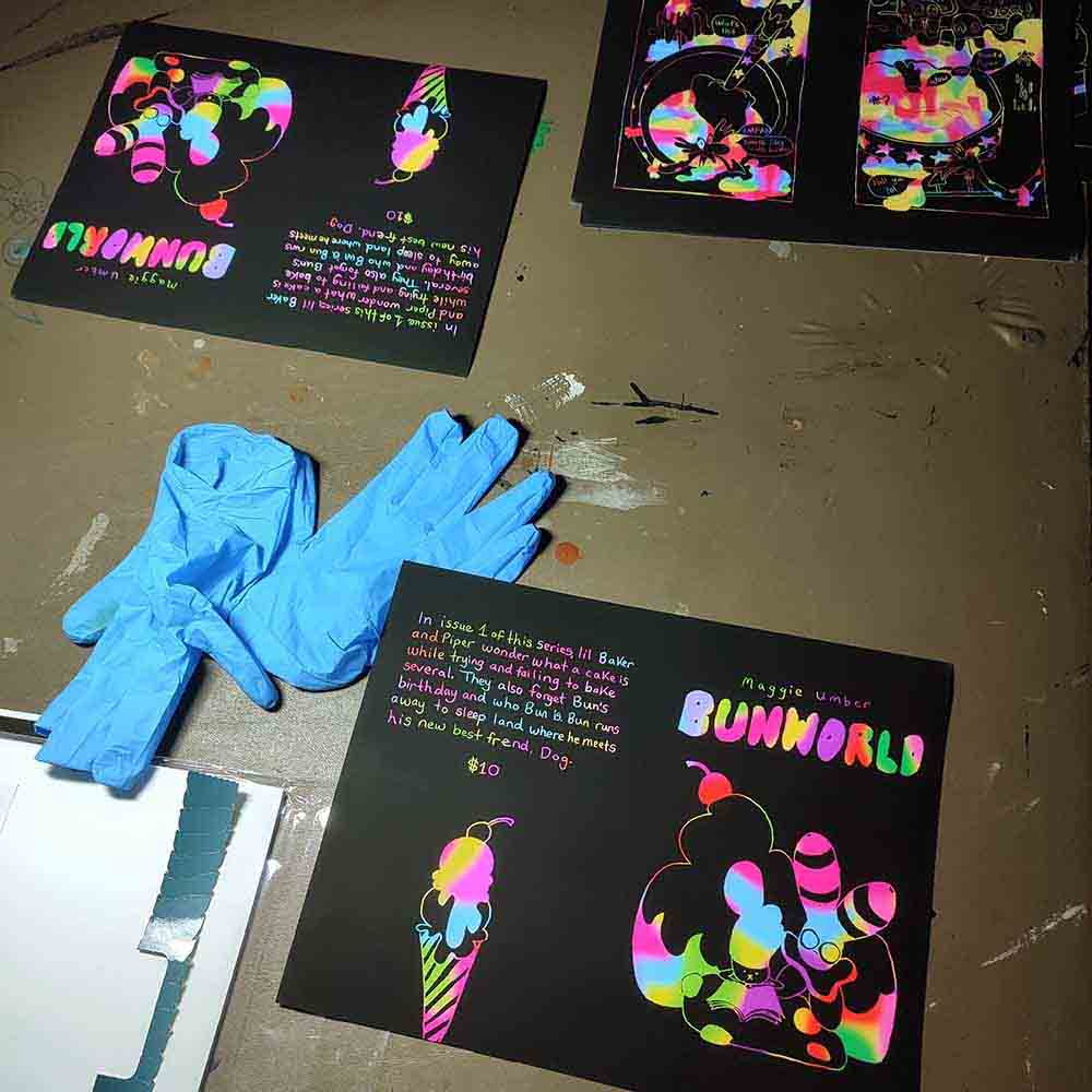 printed pages of Bunworld waiting to be folded with a pair of blue gloves