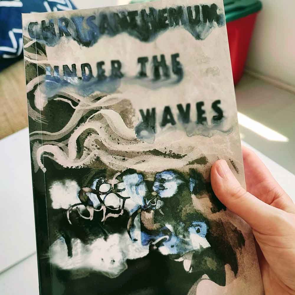 hand holding book, front cover text reads Chrysanthemum Under the Waves, Maggie Umber