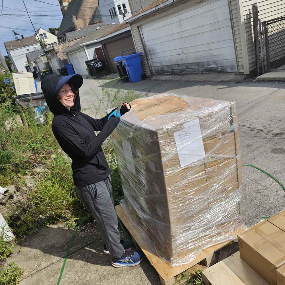 Maggie Umber unpacking a pallet of Chrysanthemum Under the Waves graphic novels